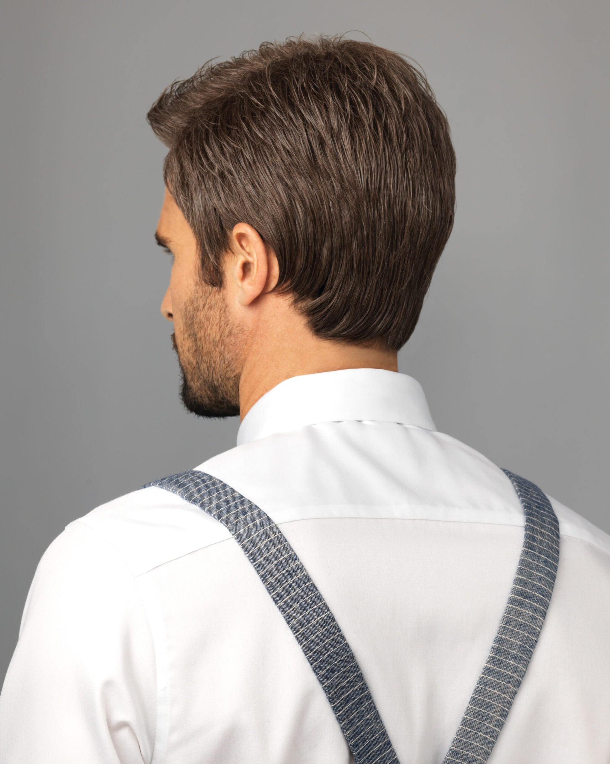 HIM Style men's wig by HairUWear on model back view short brown textured hair with dress shirt and suspenders