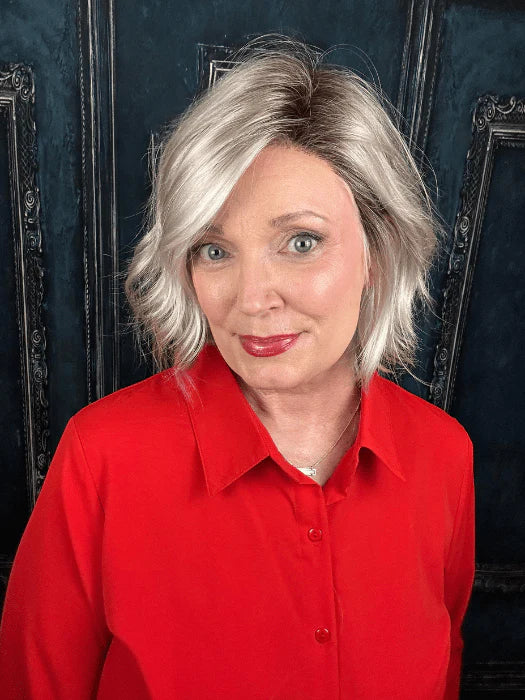 Woman wearing short silver blonde wig for women styled in layered wavy bob with side part over red blouse
