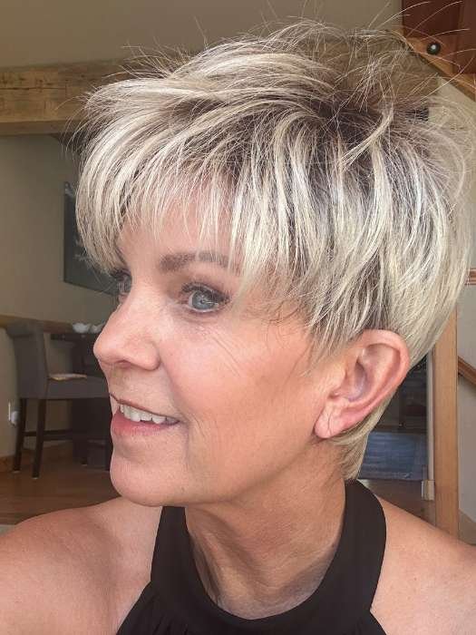 Short blonde synthetic wig on mature woman styled as layered pixie with textured bangs and natural finish