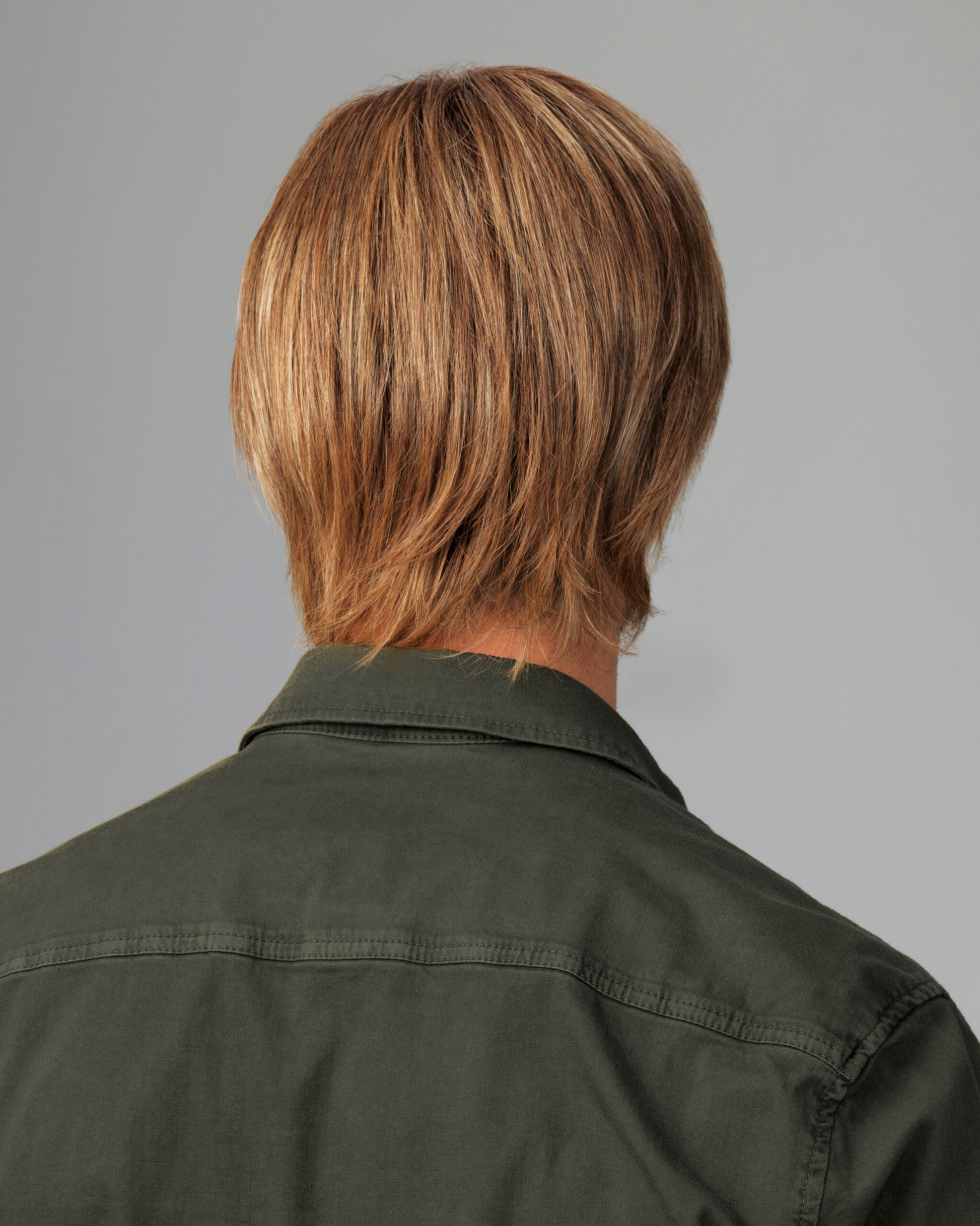 Back view of a HairUWear men's chiseled wig in sandy brown layered cut on a model wearing an olive shirt