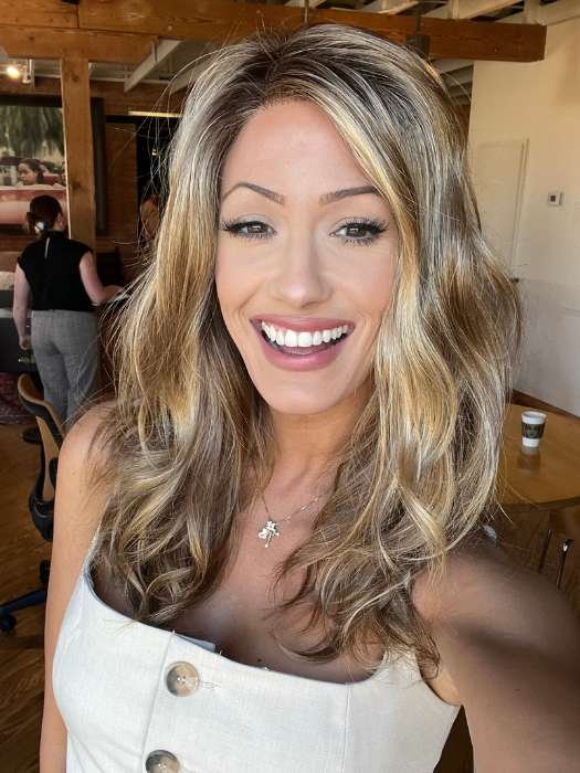 Smiling woman wearing Ellen Wille Arrow lace front wig in blonde highlights with natural waves